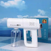 A white portable nano spray machine is shown next to its bottle and packaging box against a blue sky background.
