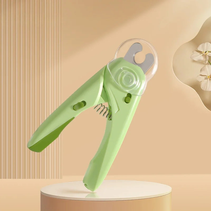 A light green pet nail clipper tool is displayed on a round stand against a beige background.