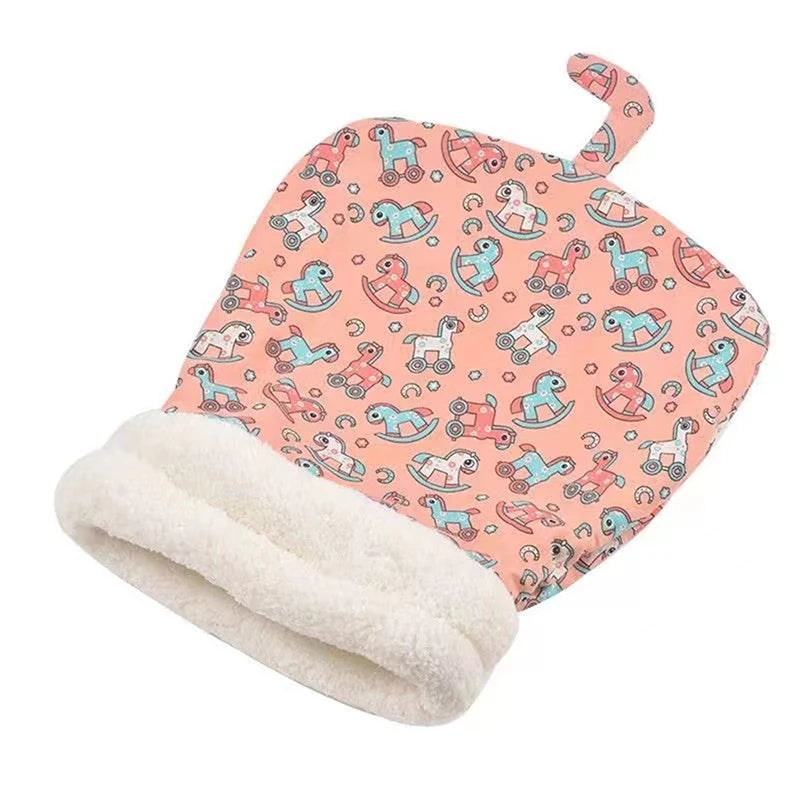 A pink fabric cat bed with a repeating pattern of cartoon cats and a white fleece blanket.