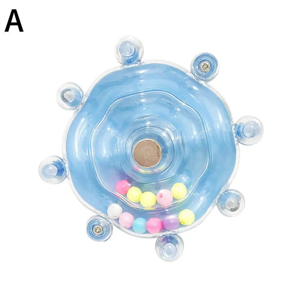 A rotating parrot treat dispenser with a light blue, translucent body and colorful spherical treats inside.