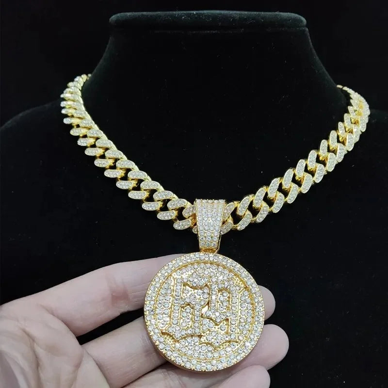 A gold-toned Cuban link chain necklace with an iced out letter and animal pendant displayed on a black velvet display.
