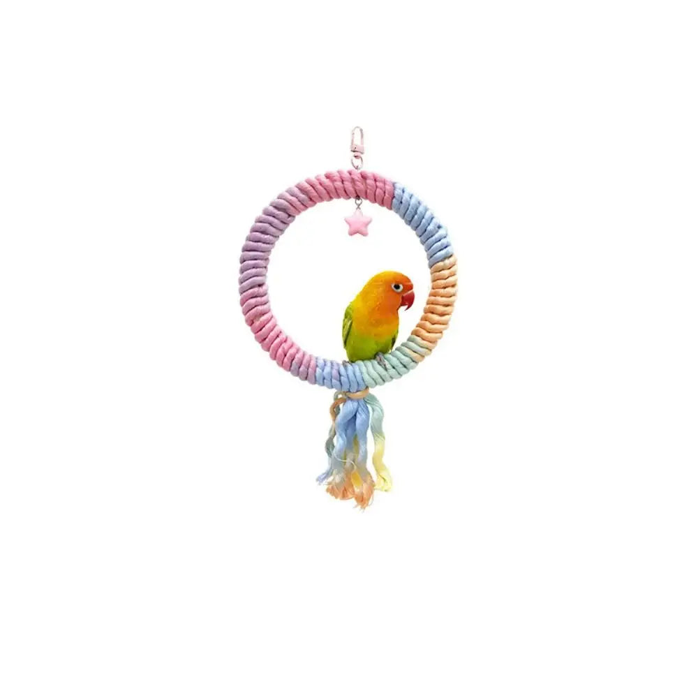 A yellow parrot is perched on a pink cotton rope perch with a small star charm.