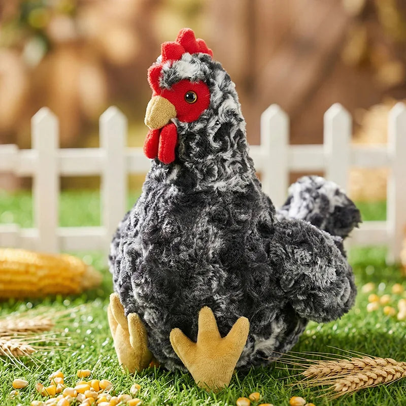 A fluffy black and white plush rooster and hen set sitting on green grass with wheat stalks.