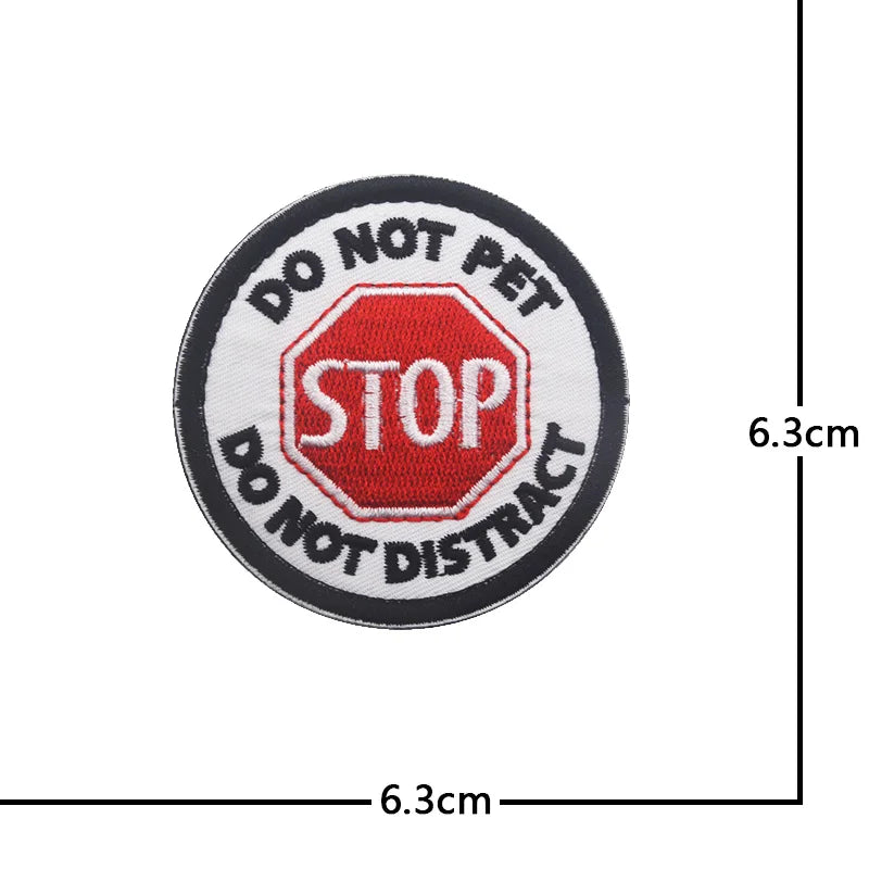 Black circular patch with red and white text DO NOT PET STOP DISTRACT embroidered on it