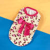 A pink and white leopard print knit pet sweater with a pink bow displayed on a blue background.