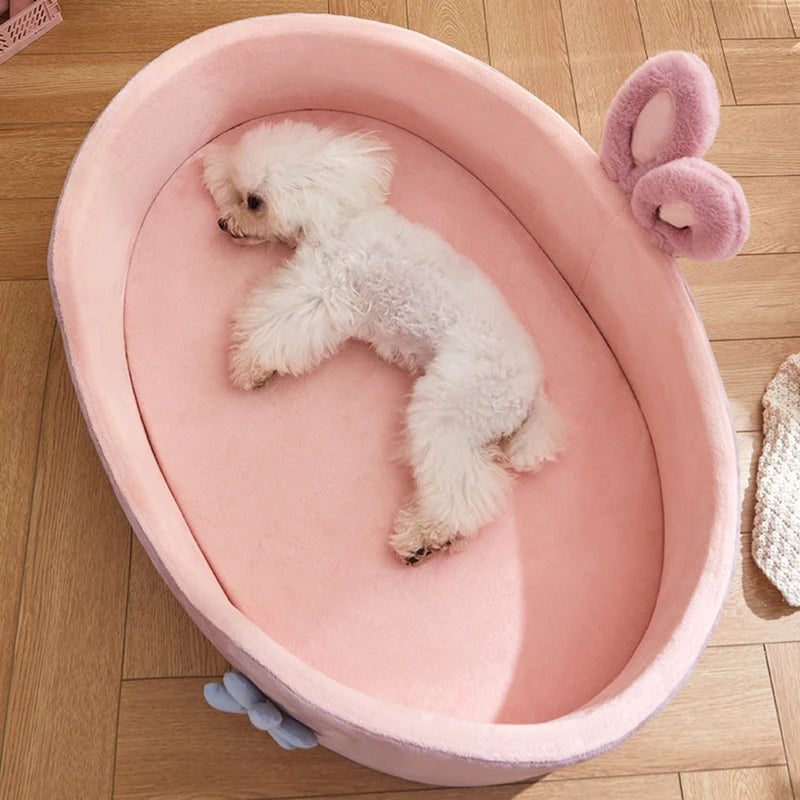 A fluffy white puppy is resting inside a pink plush pet bed with a removable cover.