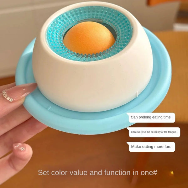 A white feeding toy with a blue lid is shown, designed to prolong eating time and make feeding fun.
