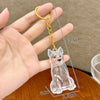 A clear, puppy-shaped pet hair keepsake keychain is held in a hand, showing its size and detail.