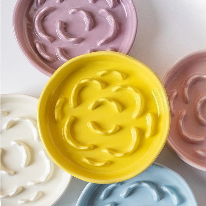 A collection of colorful ceramic pet bowls in various shades including yellow, pink, and blue.