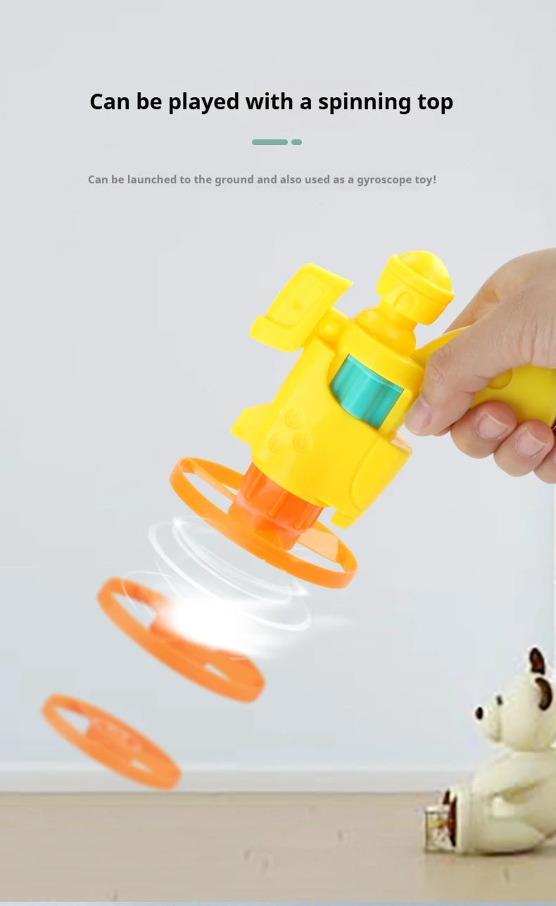 A hand is launching an orange spinning disc toy towards a white cat figurine.