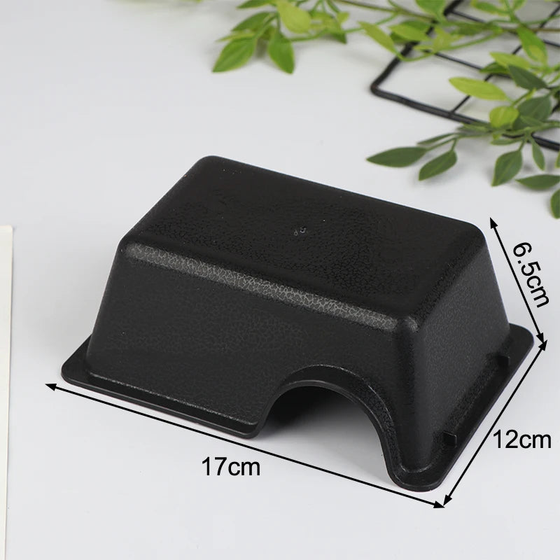 A black reptile hide box enclosure with a slightly curved shape is shown on a white surface.