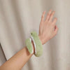 A hand is holding a soft, bendable plush toy resembling a green snake.