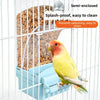 A yellow bird is feeding from a semi-enclosed, splash-proof bird feeder inside a wire cage.