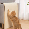 An orange tabby cat is scratching against a beige sisal cat scratching mat placed on a gray sofa.