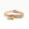 Pink and yellow lace flower cat collar with a gold bell and light gray buckle.
