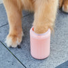 A dog's paw is dipped into a pink silicone cup for cleaning.