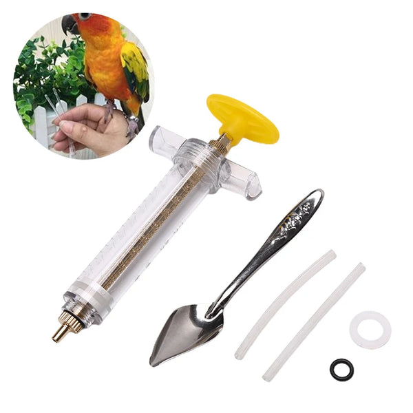 A clear plastic syringe with a yellow tip and a metal spoon for feeding parrots, shown next to a bird.