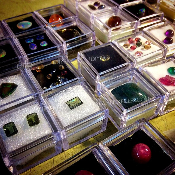 Clear square storage boxes filled with various colorful craft supplies and gemstones