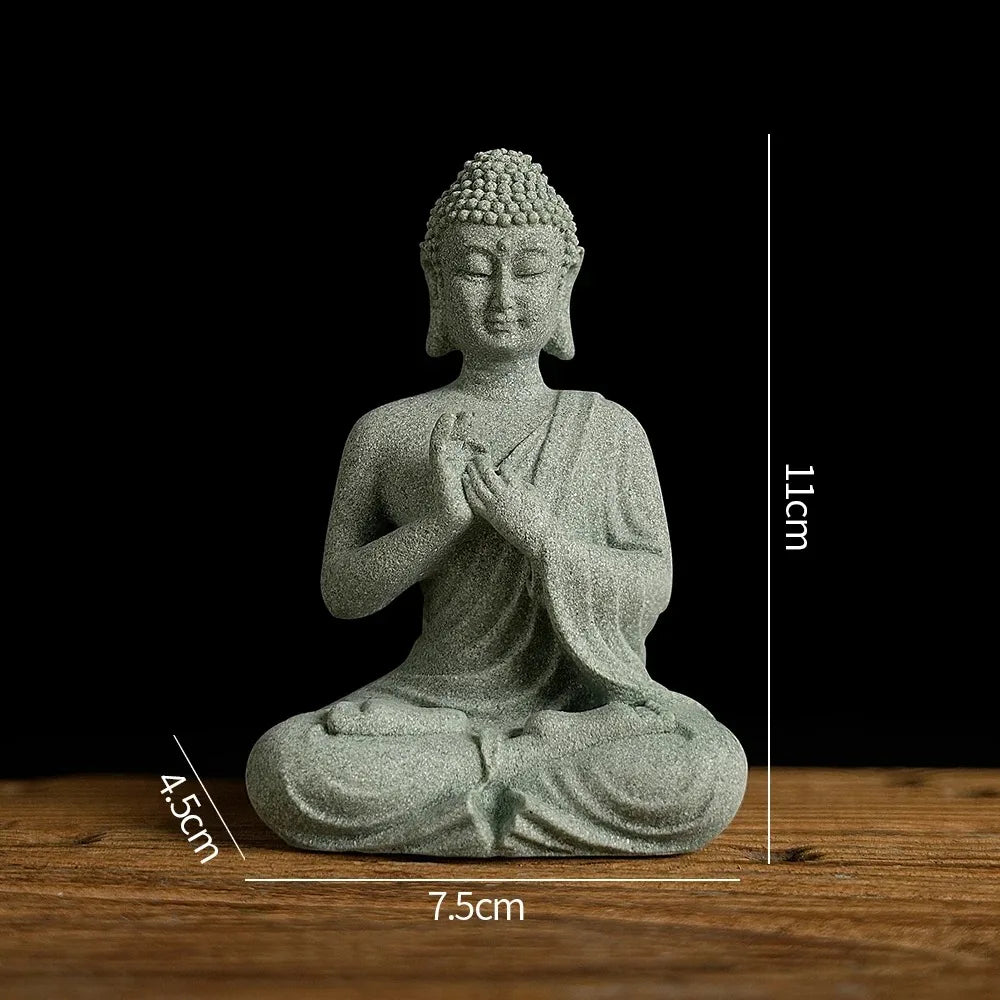 A small, gray Buddha stone statue in a seated meditation pose, displayed on a wooden surface.