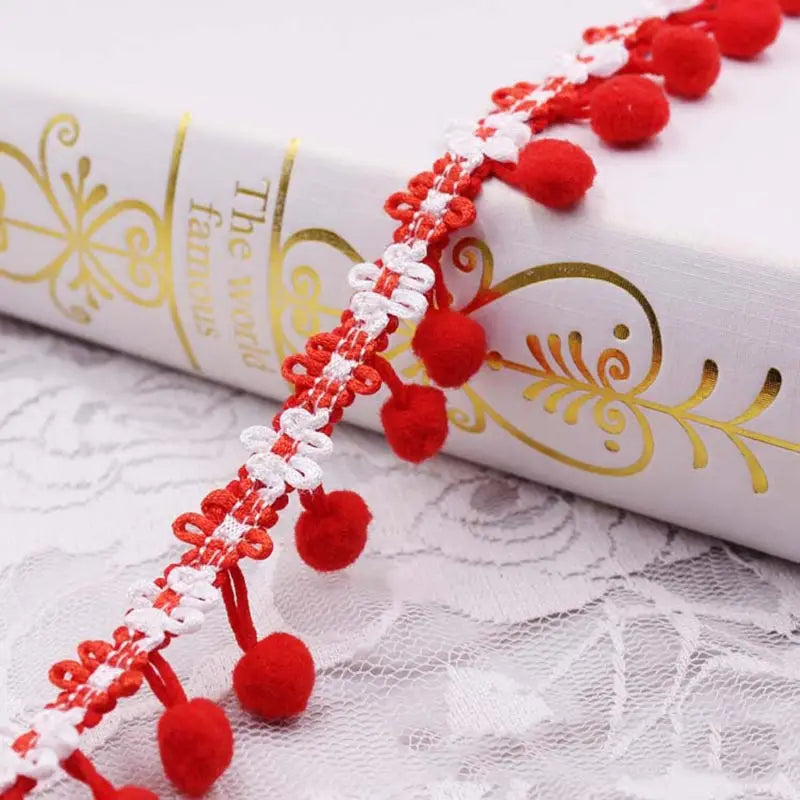 Red and white pom pom fringe lace trim decoration on a white book cover