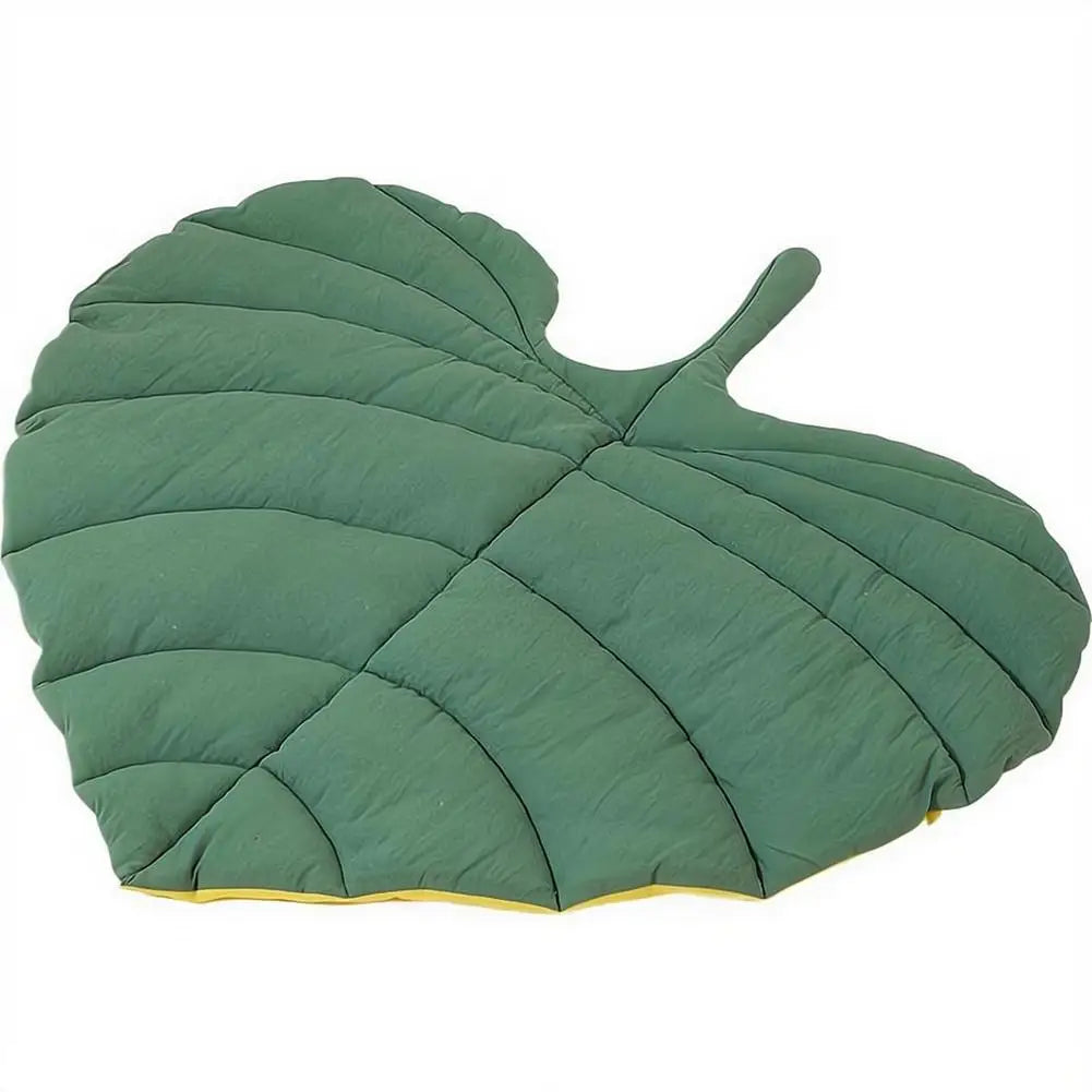 A reversible leaf-shaped pet mat in olive green fabric with yellow trim.
