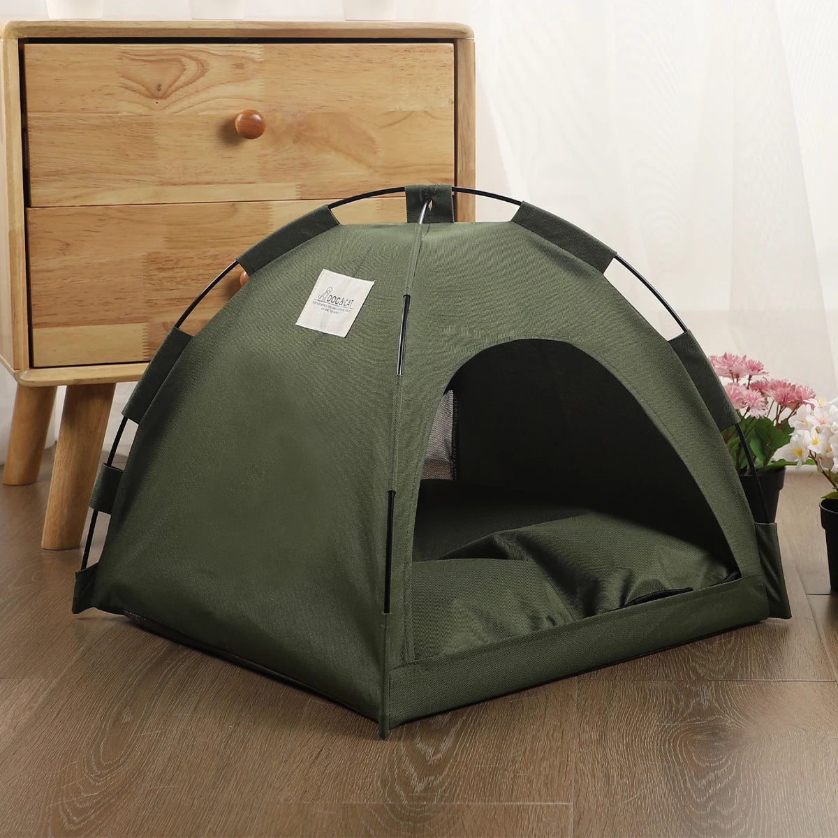 Lit de voyage pour chat, vert olive foncé, avec toit incurvé et côtés en filet, posé sur une surface en bois.