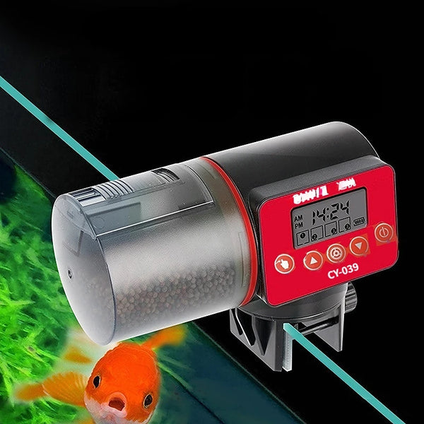 A black automatic aquarium fish feeder with a red control panel is shown over a green aquatic background.