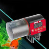 Rotes und silbernes automatisches Fischfuttergerät mit einem Goldfisch im Hintergrund