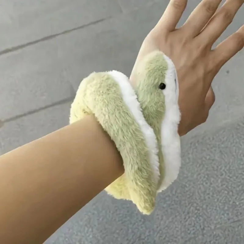 A hand is holding a soft, bendable plush toy resembling a green and white snake.