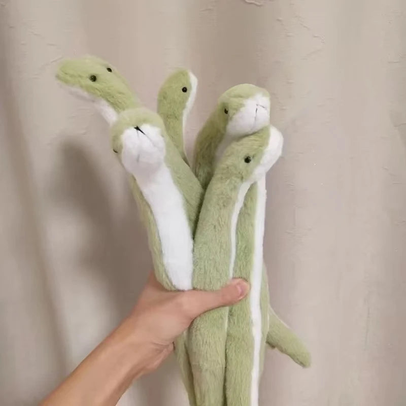 A hand is holding a soft, bendable plush toy resembling a green snake with white markings.