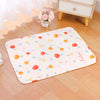 A pink and orange floral patterned soft cotton pet cage mat with a non-slip base placed on a wooden floor.