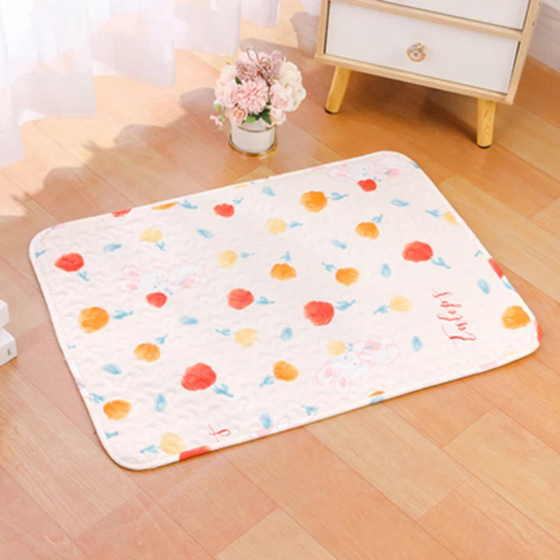 A pink and orange floral patterned soft cotton pet cage mat with a non-slip base placed on a wooden floor.