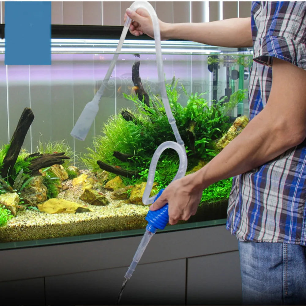 A person uses a clear siphon cleaner tool to clean the water in an aquarium.