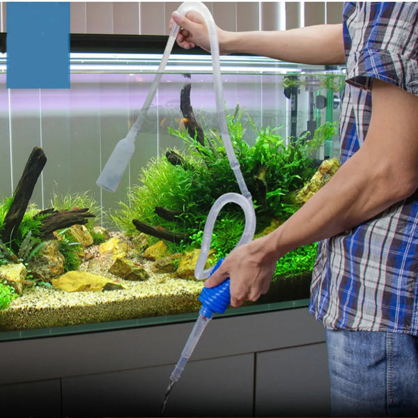 Una persona usa una herramienta de sifón transparente para limpiar el agua de un acuario.