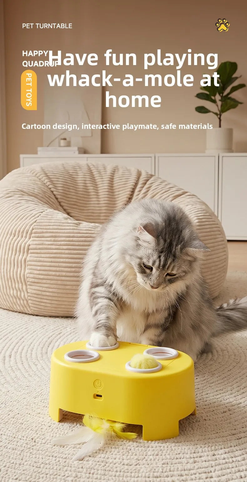 A yellow rechargeable whack-a-mole cat toy with replaceable feather balls is shown on a light-colored rug.