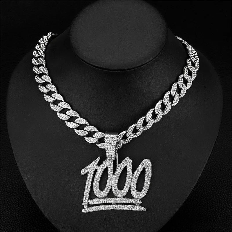 A silver iced out letter and animal pendant Cuban link chain necklace displayed on a black display stand.