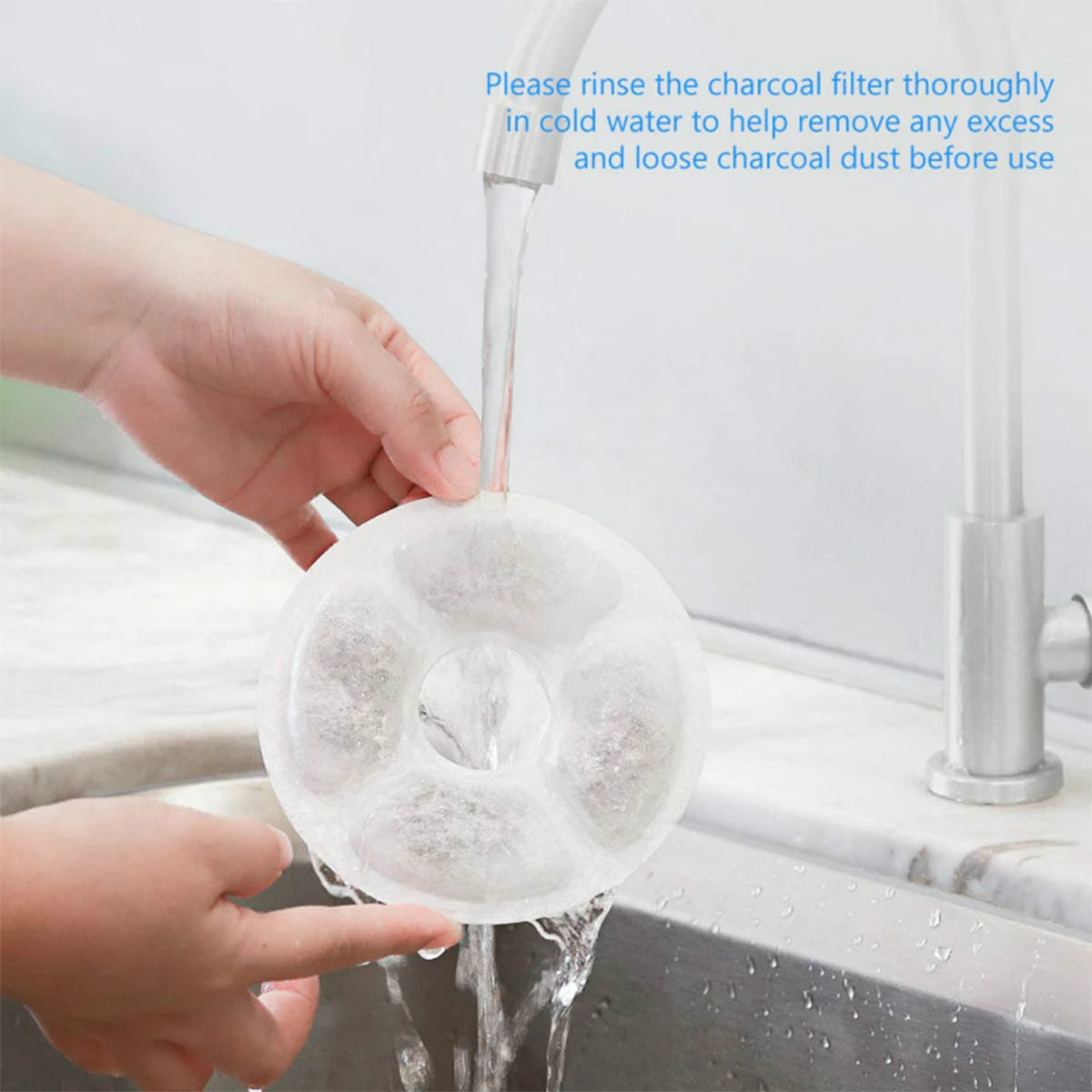 Hands rinse a white activated carbon filter thoroughly in cold water before use.