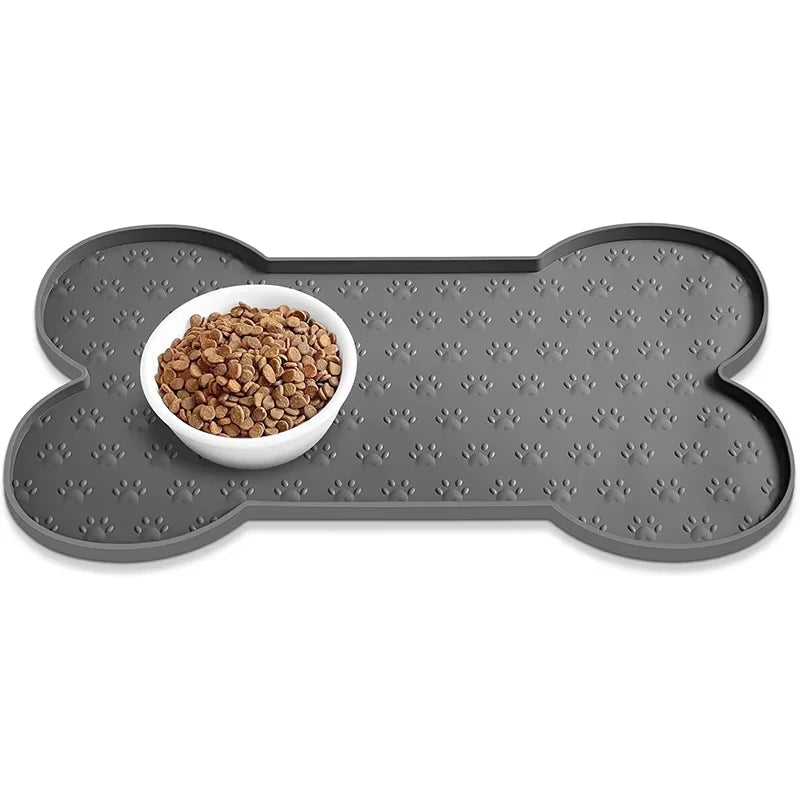 A gray silicone pet feeding mat with a raised edge holds a white bowl filled with dry pet food.