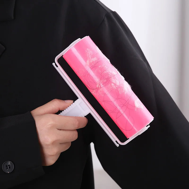 A hand holds a pink reusable lint roller against a black suit jacket.