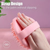 A hand is holding a pink silicone body exfoliating brush, demonstrating its grip design.