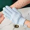 A hand wearing a light blue exfoliating shower glove is shown with small exfoliating particles on the skin.