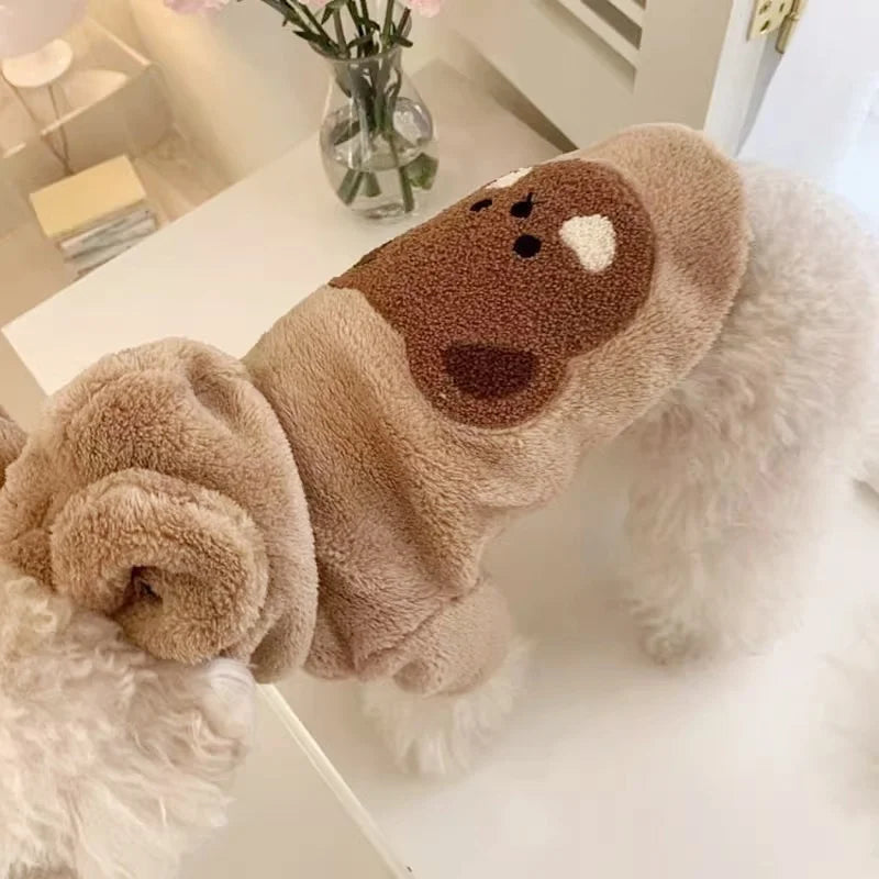 Un pull en polaire blanc et marron avec une bordure duveteuse pour chien, exposé sur une surface blanche.
