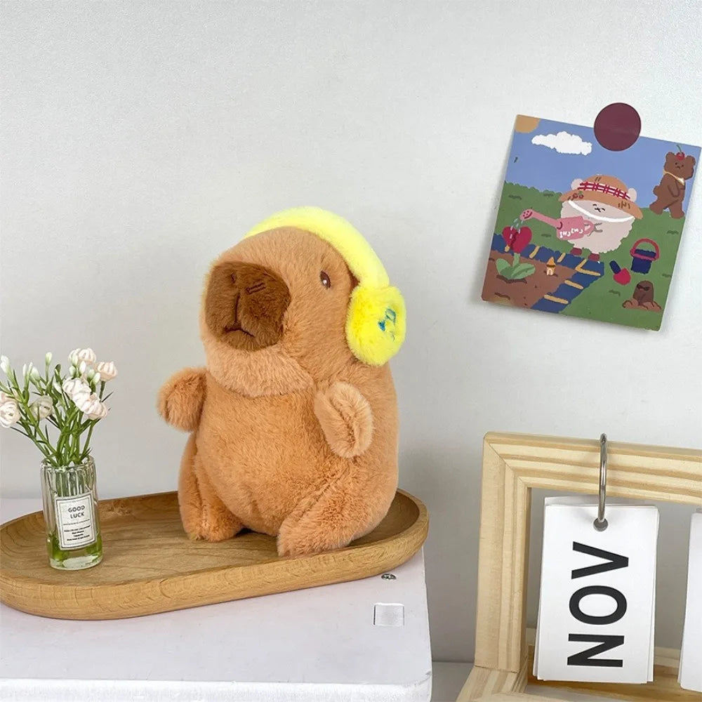 Flauschiges braunes Capybara-Plüschtier auf einem Holzbrett neben einem gerahmten Bild.