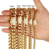 A hand holds several gold-toned stainless steel curb chain bracelets of varying lengths.