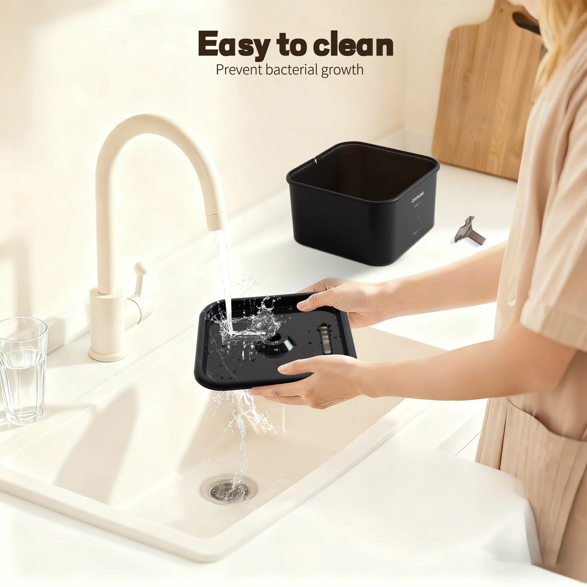 A person is cleaning a sink with a black water fountain device, demonstrating its easy to clean feature.