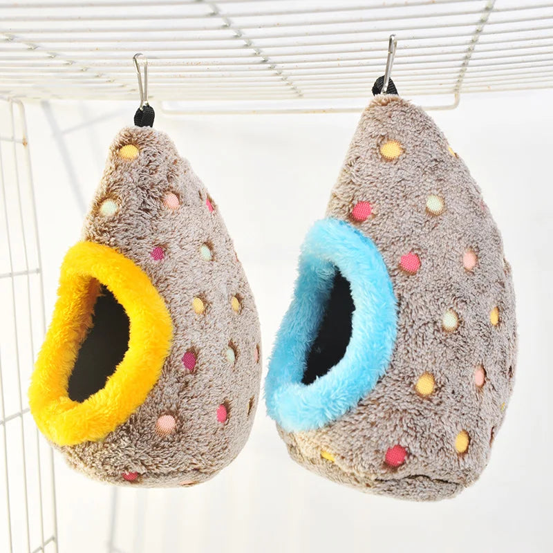 A fluffy, gray bird nest with a bright yellow entrance and a blue interior is shown hanging from a wire grid.