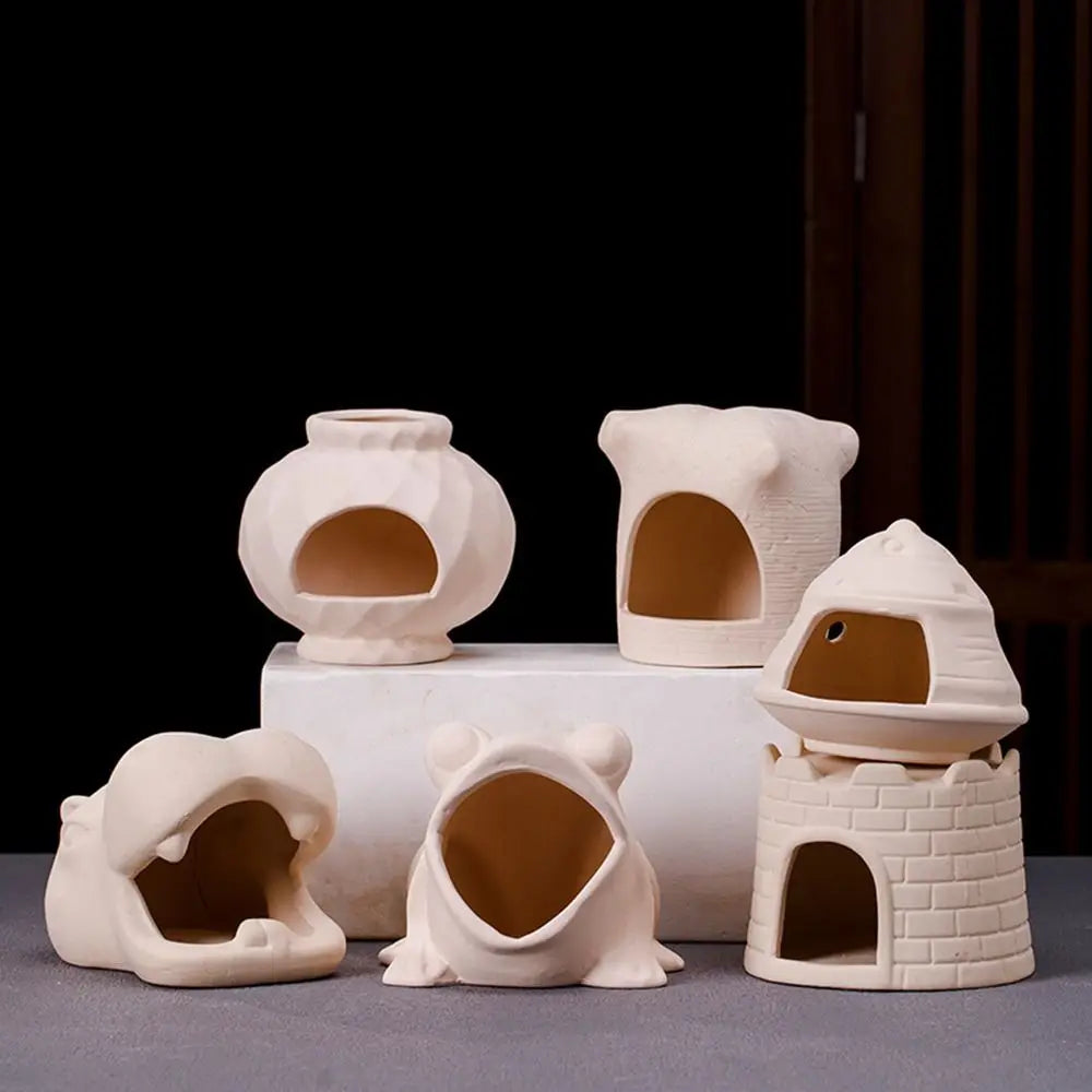 A set of ceramic aquarium shrimp hideaway caves in a light beige color displayed on a gray surface.