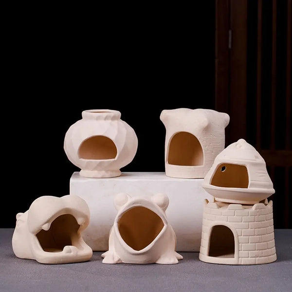A set of ceramic aquarium shrimp hideaway caves in a light beige color displayed on a gray surface.