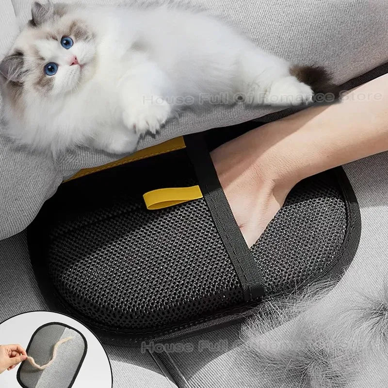 A fluffy white kitten is resting on a black grooming glove used for pet hair removal.