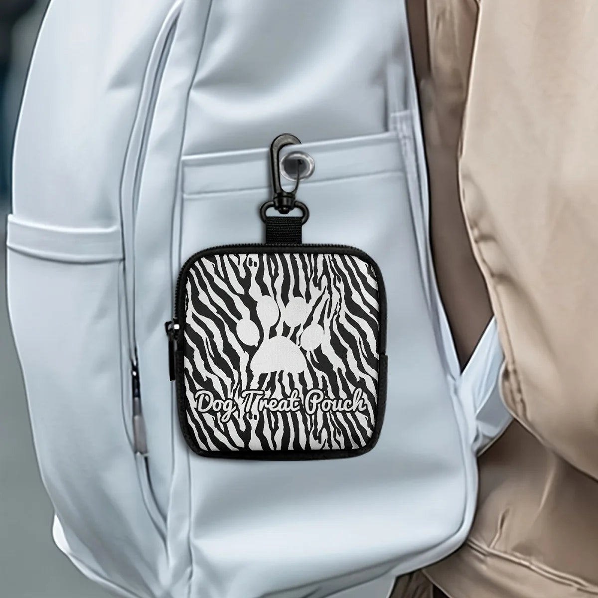A black leather pet treat pouch with a zebra print is clipped onto a white backpack.